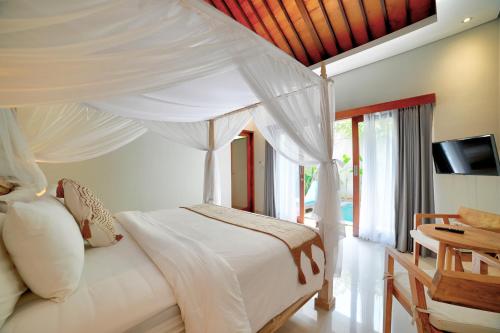 a bedroom with a white bed with a canopy at Villa LAKSMI in Seminyak