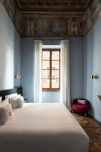 a bedroom with a large bed and a window at Palazzo Talìa - Small Luxury Hotels of the World in Rome