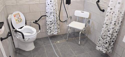 a bathroom with a toilet and a chair in it at Accesible countryside retreat with private garden and all modern facilities in Chassenon