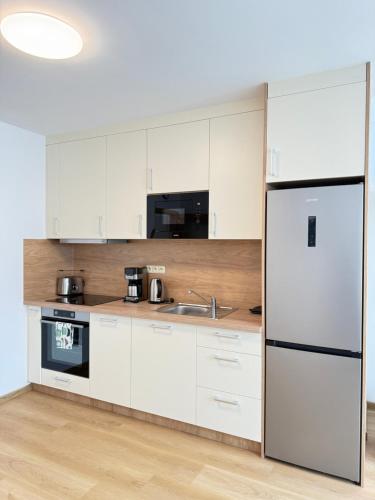 a kitchen with white cabinets and a refrigerator at Riverside Apartment Praha in Prague