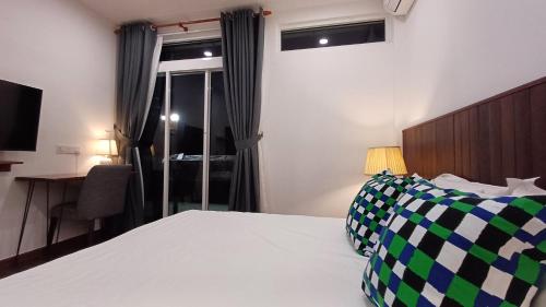 a bedroom with a bed and a desk and a window at Sling & Stone Mountain Suites in Kundasang