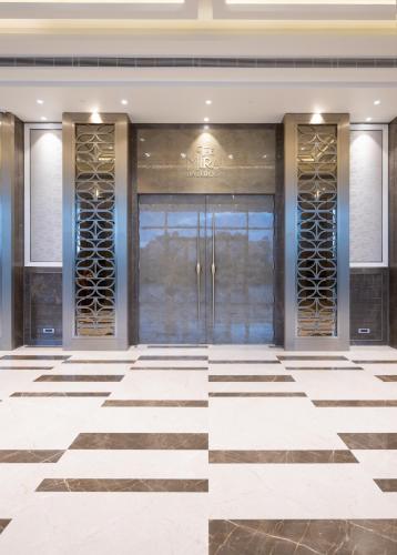 a lobby with a glass door with a checkered floor at Merlis Hotel Coimbatore in Coimbatore