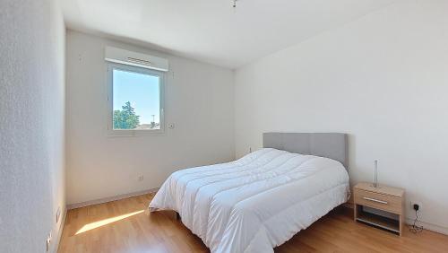 a white bedroom with a bed and a window at S-L'esquirot 01-Appartement spacieux au cœur de Soustons in Soustons