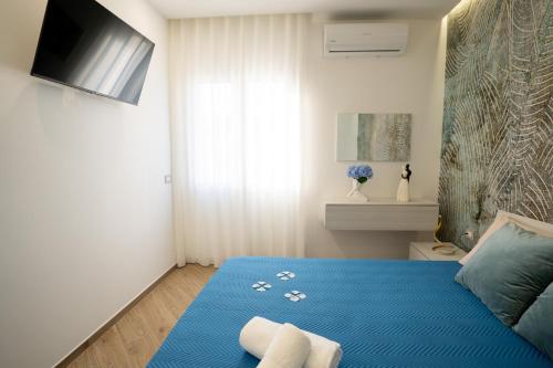 a bedroom with a blue bed with a tv on the wall at Casa Vacanze Stella Marina in Marina di Palma