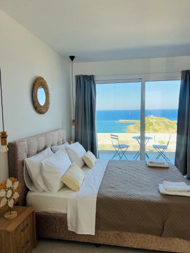 a bedroom with a bed with a view of the ocean at Grande Blue Suites with private bay in Archangelos