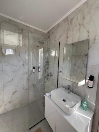 a white bathroom with a sink and a shower at Grande Blue Suites with private bay in Archangelos