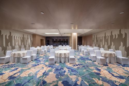 a conference room with white tables and white chairs at Merlis Hotel Coimbatore in Coimbatore