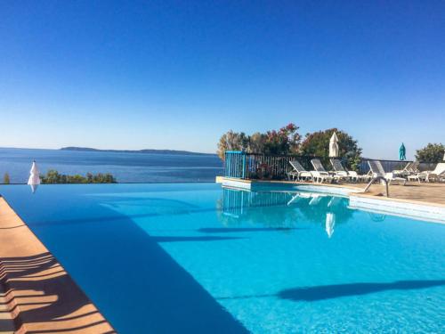 a blue swimming pool with chairs and the water at MAZET - Domaine de la Pinède PRAMOUSQUIER - Le Lavandou in Le Lavandou