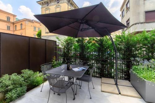a patio with a table and an umbrella at LA TERRAZZA - Downtown Como - Terrace and Jacuzzi in Como