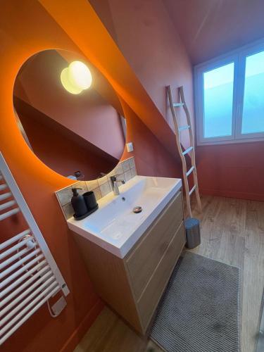 La salle de bains est pourvue d'un lavabo et d'un miroir circulaire. dans l'établissement Maison Gabanne, au Croisic