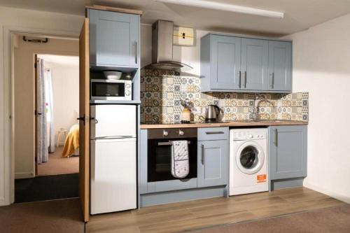 a kitchen with blue cabinets and a washer and dryer at Swingletree Cottage in Bridlington