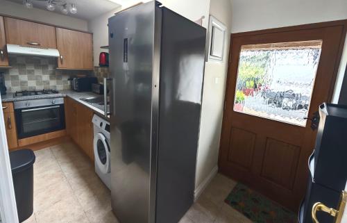 a stainless steel refrigerator in a kitchen with a window at Charmante petite maison de campagne in Le Tréhou