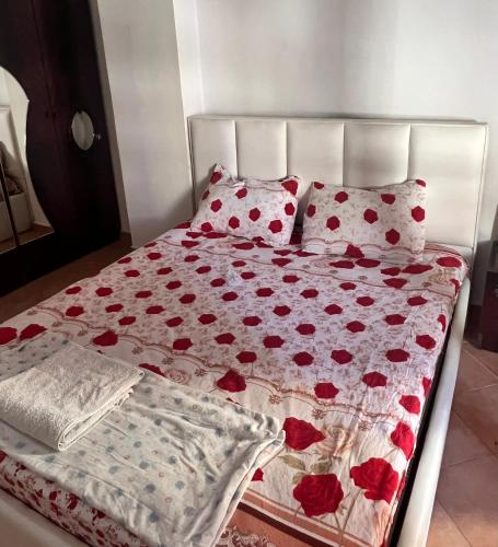 un letto con fiori rossi sopra e due cuscini di Inn house a Tirane