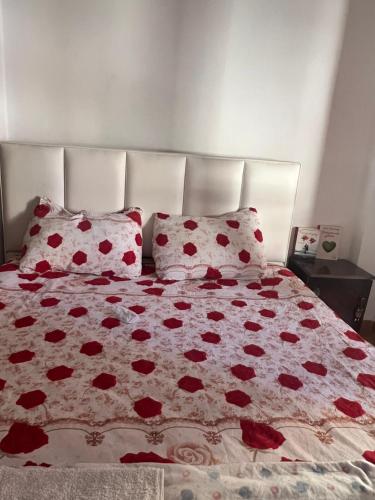 un letto con fiori rossi sopra e due cuscini di Inn house a Tirane