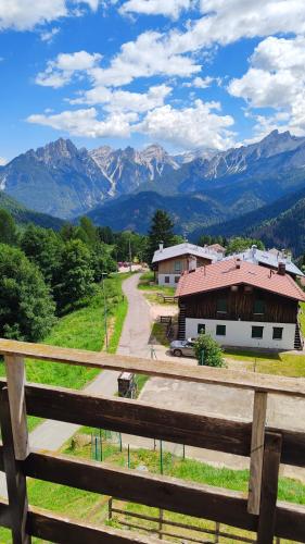 a fence with a view of a house and mountains at HG Hotel La Caminatha in Val di Zoldo