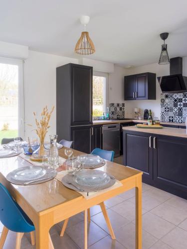 une cuisine avec une table en bois et des plaques de cuisson. dans l'établissement Escapade à Ploubalay : Maison moderne de plain-pied, à Beaussais sur Mer