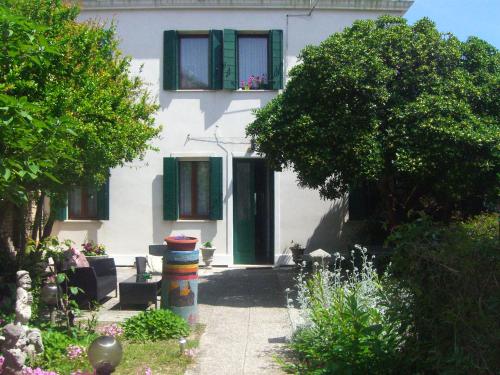 a white house with a green door and windows at Ca' Del Pomo Grana' in Murano