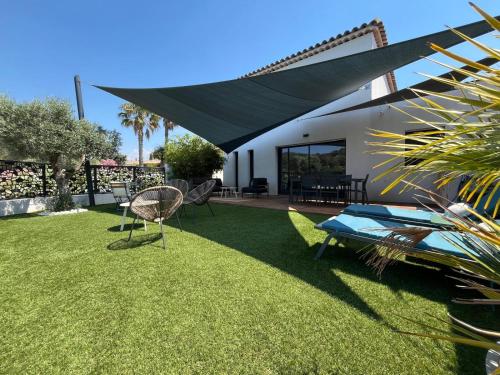 une cour avec une pelouse, une table et des chaises dans l'établissement Le Castellet Maison de vacances, au Castellet