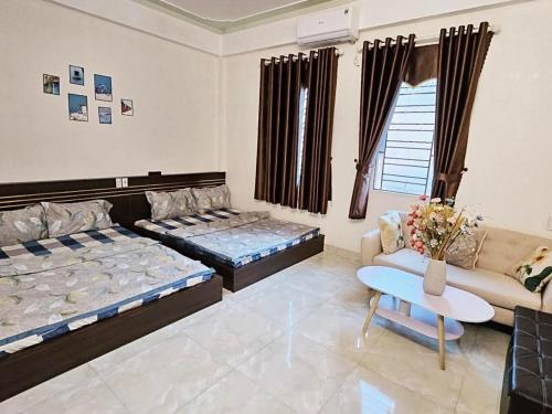 a living room with two beds and a couch at Nhà Của Mai in Mộc Châu