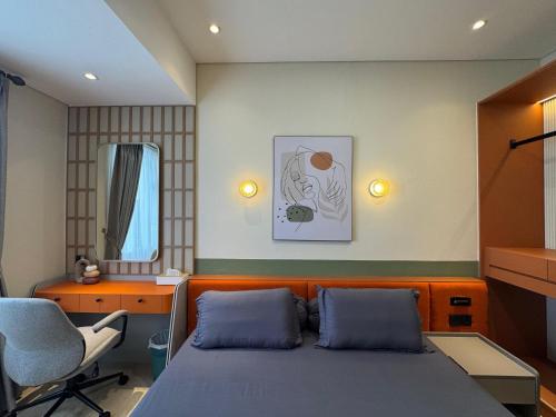 a bedroom with a bed and a desk and a chair at Podomoro Medan Lexington Tower - Japandi Modern - New Renovated 2 BR- direct mall access in Medan
