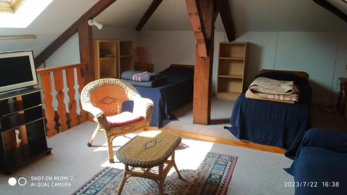 Habitación con 2 camas, TV y sillas. en Maison de maître, en Sabres