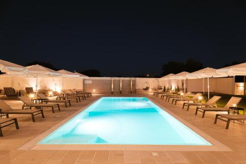 a swimming pool at night with chairs and umbrellas at Eleia Domos in Monopoli
