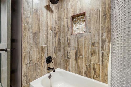 a bathroom with a tub and a wooden wall at Brighton Bonanza in Brighton