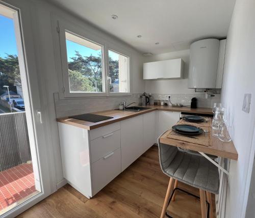 une cuisine avec des armoires blanches et une table avec des chaises dans l'établissement Suite Laosk, à Pornichet