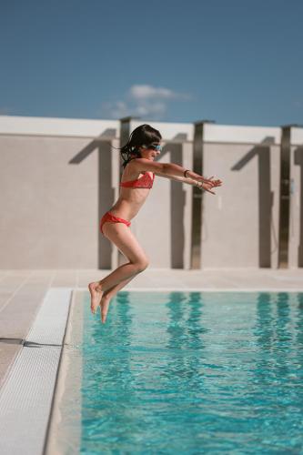 a woman in a red bikini jumping into a swimming pool at Eleia Domos in Monopoli