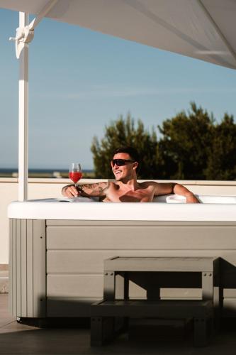 a man in a bath tub with a glass of wine at Eleia Domos in Monopoli