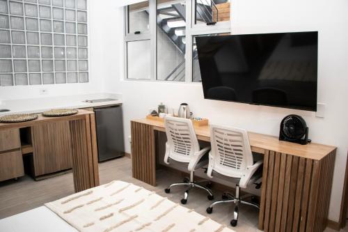 a kitchen with a desk with two chairs and a large tv at Zenia 70 Living & Suites in Medellín