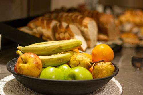 a bowl of fruit with bananas apples and oranges at NBH Premier Hotel in San Carlos de Bariloche