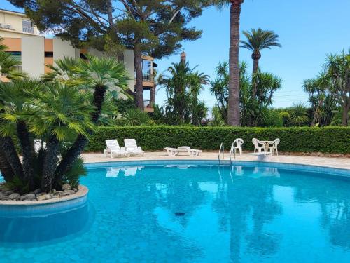 - une piscine avec des chaises et des palmiers dans un complexe dans l'établissement Superbe appartement plage du Midi 2 piscines 325L, à Cannes