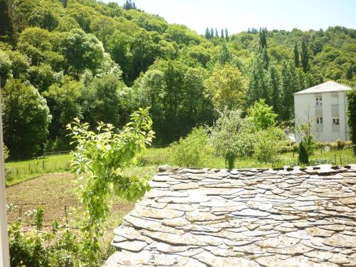 a stone wall in a garden with a house in the background at Pensión Santa Rosa in Samos