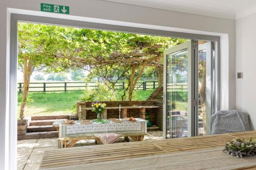 a sliding glass door to a patio with a table at Lower Barn House at Westerlands Farm Sleeps 11 in Graffham