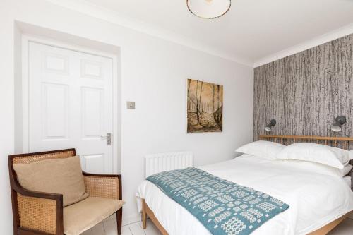 a white bedroom with a bed and a chair at Lower Barn House at Westerlands Farm Sleeps 11 in Graffham