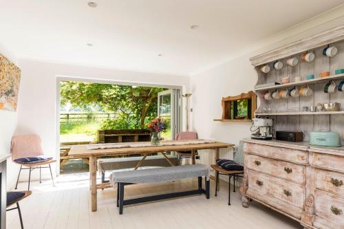 a kitchen with a wooden table and some chairs at Lower Barn House at Westerlands Farm Sleeps 11 in Graffham