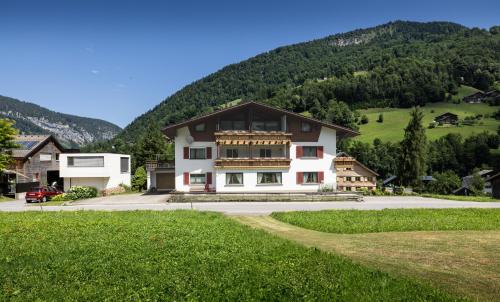 a large white house with a mountain in the background at Gästehaus Manuela Puchmayr in Mellau