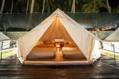 Una tienda de campaña con dos camas sobre un suelo de madera. en Nirvana Beach Villages, en Ấp Long Sơn