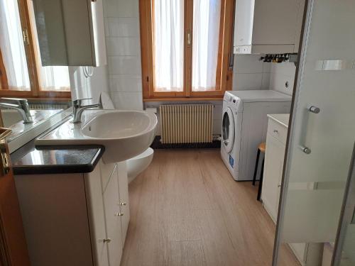 a bathroom with a sink and a washing machine at Appartamento Maurizio in Spormaggiore