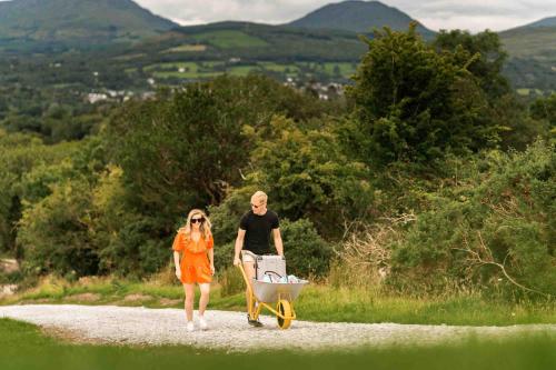 a man pushing a woman with a wheelbarrow at Oaklane Glamping Cabins in Kenmare