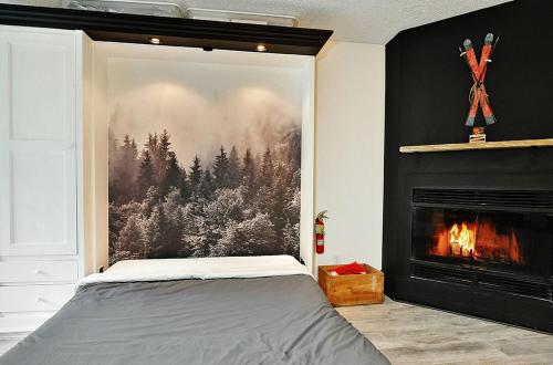 a bedroom with a fireplace and a painting of a forest at Hameau 28-51 Studio in Stoneham
