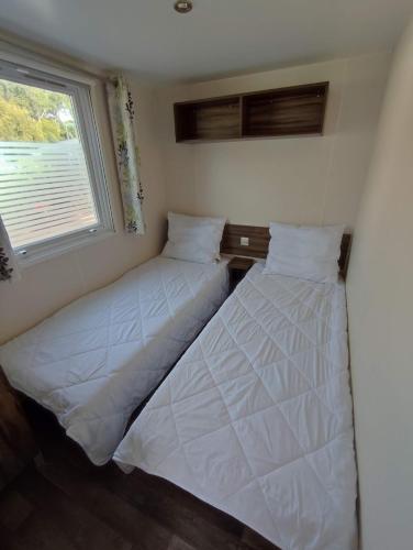 deux lits dans une petite pièce avec une fenêtre dans l'établissement Mobile-Home 4 personnes Camping 5*, à Saint-Georges-de-Didonne