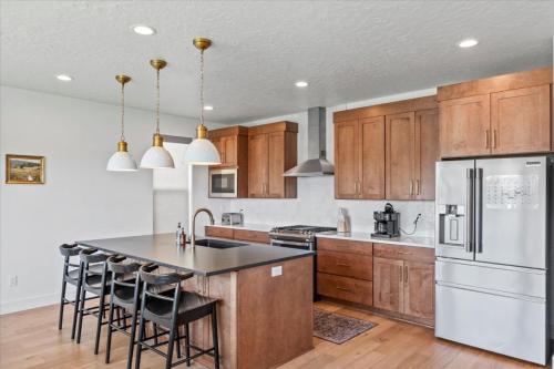 a kitchen with wooden cabinets and a kitchen island with bar stools at Cherry Hill stay and play near lagoon in Kaysville