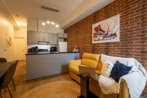 a living room with a couch and a brick wall at Sleek 2BR in Heart of Downtown Montreal in Montréal