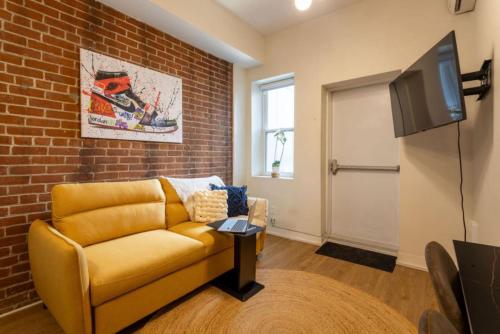 a living room with a yellow couch and a brick wall at Sleek 2BR in Heart of Downtown Montreal in Montréal