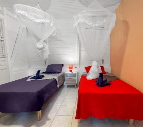 a bedroom with two beds and a red table at Évasion créole à Grande Anse in Les Anses-dʼArlets