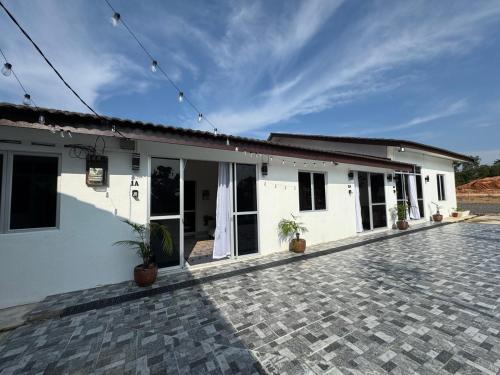 a white building with potted plants in front of it at D' Ehsan Homestay & Chalet in Kuala Terengganu