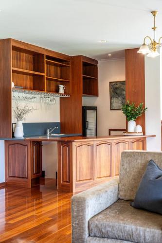 a kitchen with wooden cabinets and a couch in a living room at Secluded Stylish and Spacious The LostPlot 