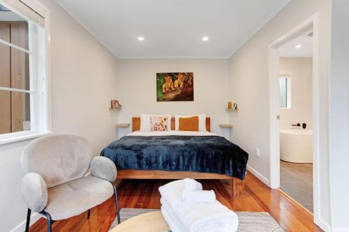 a bedroom with a bed and a chair at Countryside 4BR Family Home near Airport in Auckland